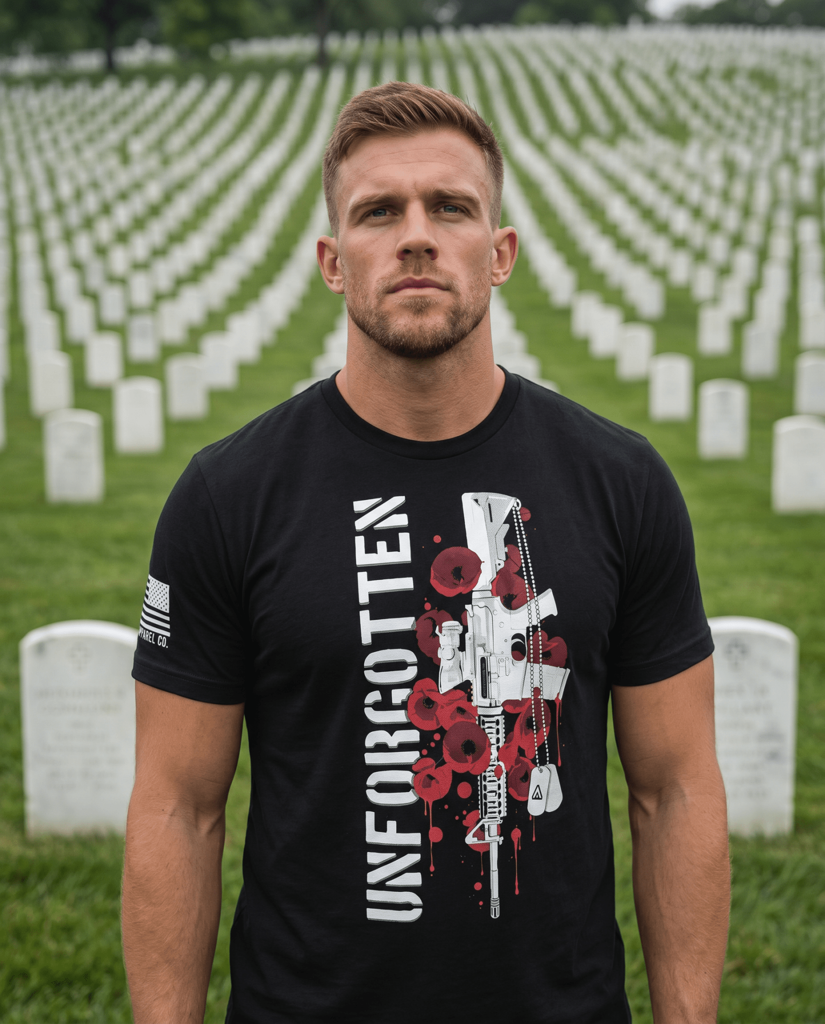 Man standing in a cemetery, wearing a black t-shirt with a rifle and poppy graphic, with a white American flag on the sleeve.