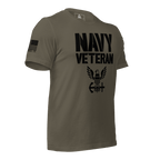 Army green t-shirt angled left, featuring black "NAVY VETERAN" text, eagle emblem, and American flag on the right sleeve.