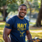 A man at a grill wearing a navy "NAVY VETERAN" t-shirt with an eagle emblem and American flag on the right sleeve.
