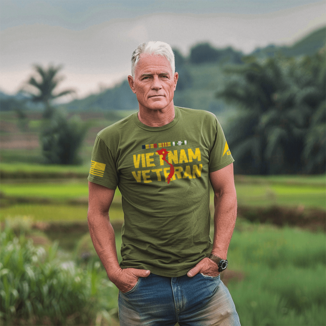 A man stands in a field wearing an army green Vietnam Veteran t-shirt with a yellow American flag and DIA logo on the sleeve.