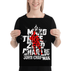 A smiling woman in a black shirt holds a poster with distressed "Mako Three Zero Charlie" text and a red graphic.