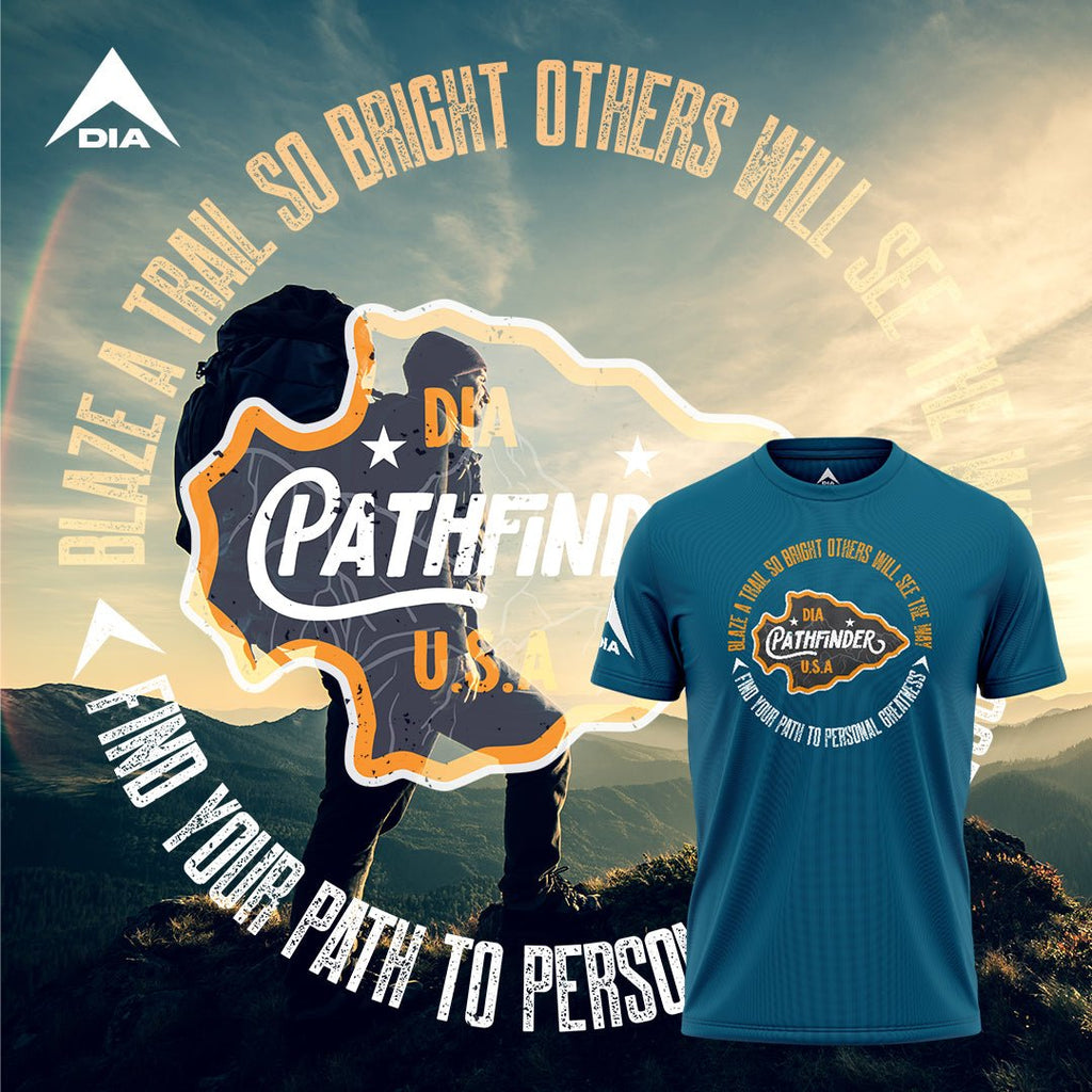 Hiker in a mountain landscape, beside a deep teal t-shirt with a white DIA logo on the sleeve and a Pathfinder graphic.
