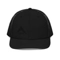 Black trucker hat with a black mesh back featuring a subtle, tonal black DIA logo embroidered on the front-left panel.